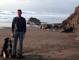 A PHOTOGRAPH  of Michael and his Australian Shepherd, Rudy, standing at the edge of the cliffs on the beach at Fort Funston.