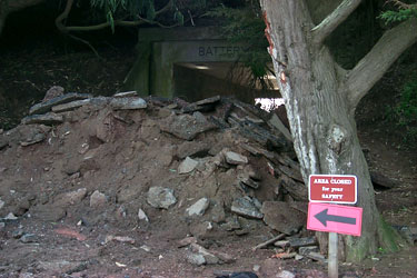 BEGINNING OF IMAGE DESCRIPTION.  IMAGE IS A PHOTOGRAPH SHOWING A HUGE PILE OF RUBBLE CONSISTING OF BROKEN-UP ASPHALT AND DIRT.  THIS PILE IS BLOCKING THE NORTHERN ENTRANCE TO BATTERY DAVIS AND THE SUNSET TRAIL.  THERE IS A SIGN NEXT TO A TREE.  THE SIGN READS AS FOLLOWS. QUOTE, AREA CLOSED FOR YOUR SAFETY. END QUOTE.  THERE IS ALSO A LARGE ARROW BENEATH THE SIGN, DIRECTING VISITORS TO TAKE THE OTHER ROUTE TO GET BACK TO THE PARKING LOT.   END OF IMAGE DESCRIPTION.